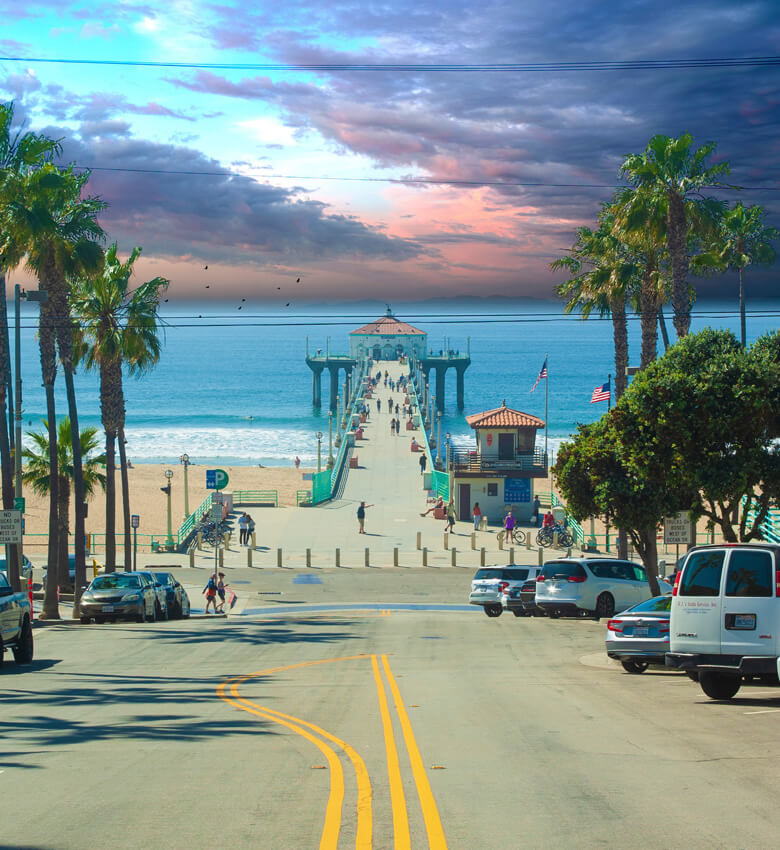 Manhattan Beach Pier illuminated by sunlight, extending over calm ocean waters.