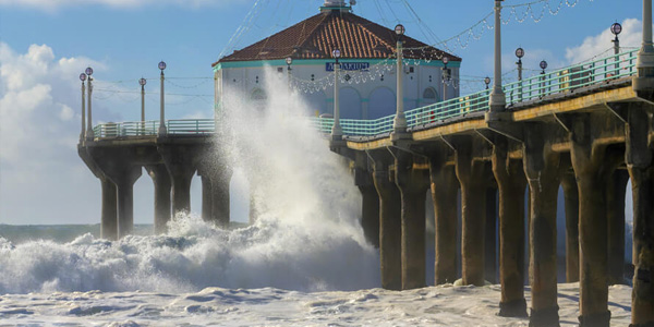Manhattan Beach Pier extending into the Pacific Ocean, framed by clear skies and gentle waves.