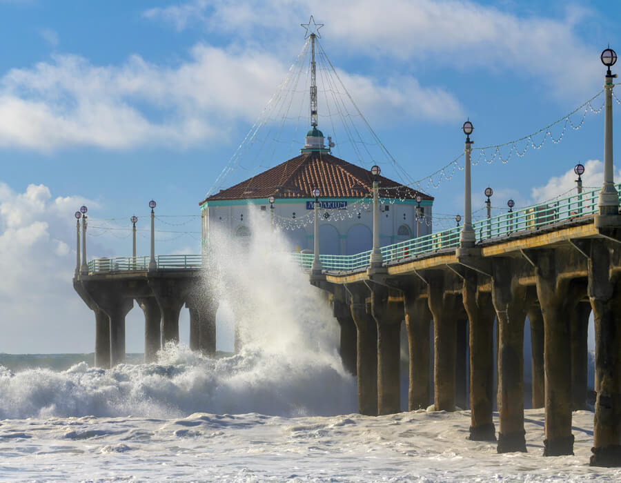 Manhattan Beach Pier extending into the Pacific Ocean, framed by clear skies and gentle waves.